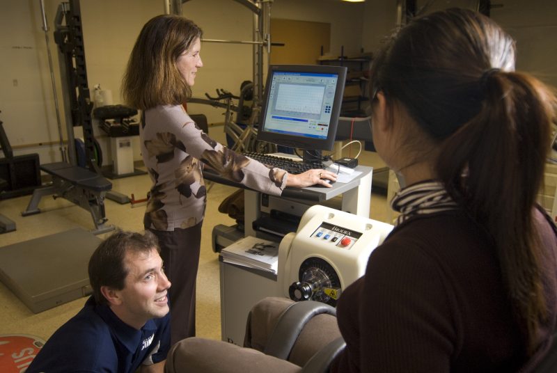 Linda Pescatella (back center), professor of kinesiology, and Matthew Kostek, graduate assistant in kinesiology, (front left), analyze a student attached to a Biodex machine in a lab in the Kinesiology department for the MS in Exercise prescription.